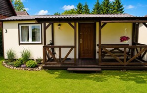 Ein eingeschossiges Haus mit einer Holzveranda, einer Haustür und der Hausnummer 3.