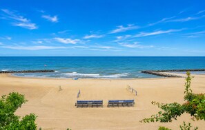 A beach with a clear sky, calm sea, and a sandy shore with seating areas. - Awesome home in Jaroslawiec with swimming pool (Jaroslawiec)