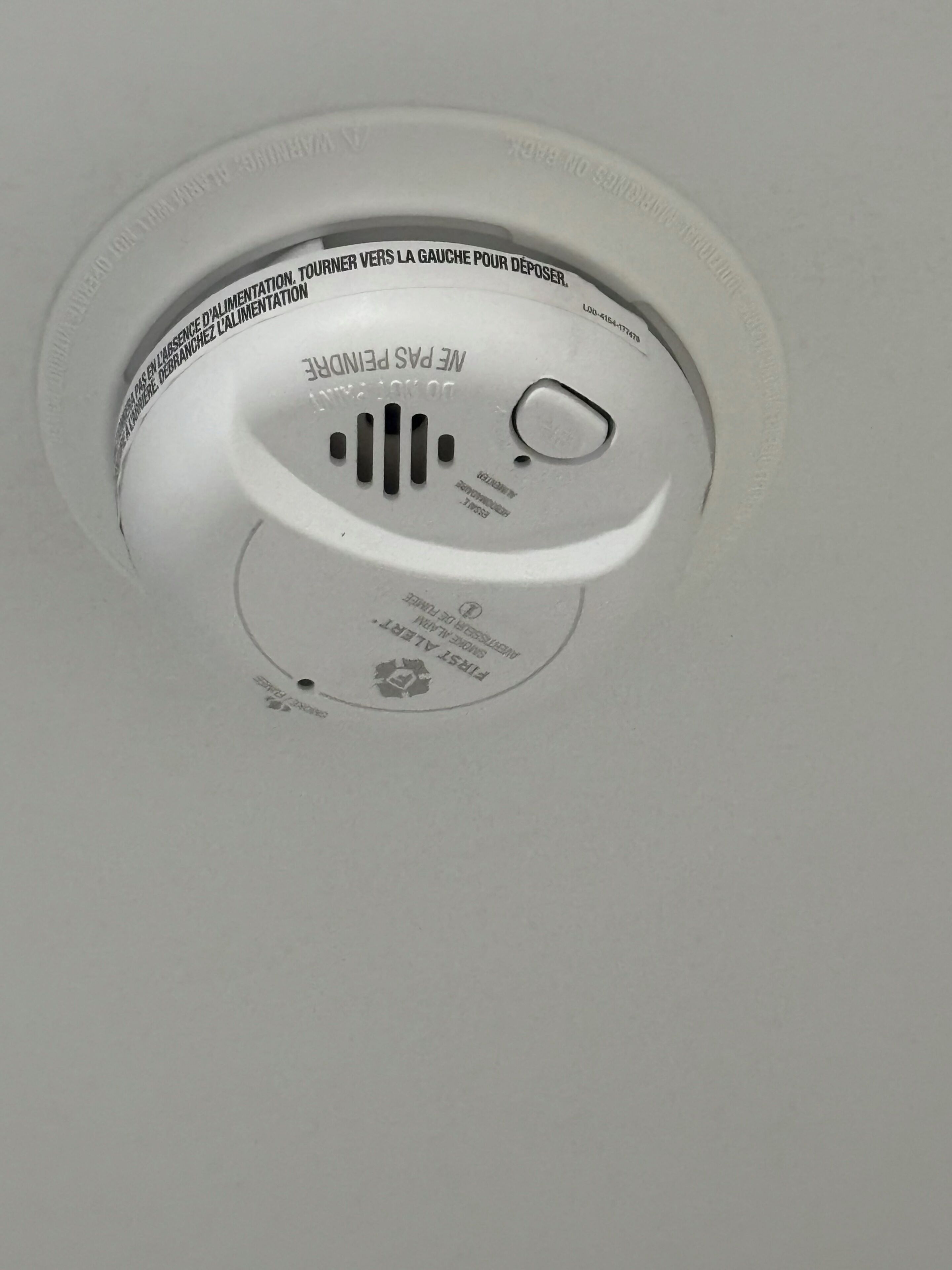 A ceiling with a smoke detector and a pull chain.