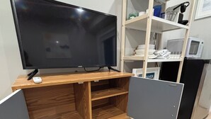 Um espaço compacto para viver, com um móvel de entretenimento de madeira, uma TV de tela plana e nichos embutidos.