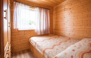 A small wooden room with a single bed, a window with curtains, and a door. - Gorgeous home in Jaroslawiec with swimming pool (Jaroslawiec)