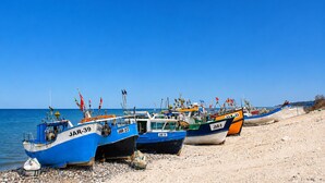Des bateaux portant des numéros d’immatriculation sont amarrés sur une plage de galets.