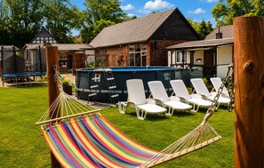 A grassy area with a hammock, white lounge chairs, and a pool. - Gorgeous home in Jaroslawiec with swimming pool (Jaroslawiec)