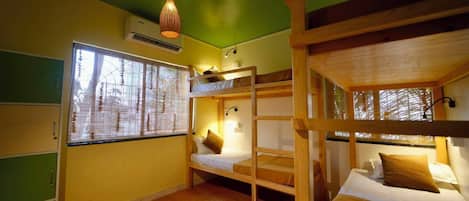 Una habitación con literas, una lámpara colgante, una ventana con persianas y suelo de madera.