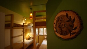 A room with bunk beds, a wooden wall decoration with text, and a hanging light fixture. - Zen Colive (Pune)