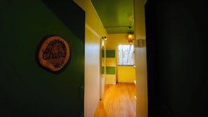 A hallway with a wooden sign on the wall, a window, and a door. - Zen Colive (Pune)