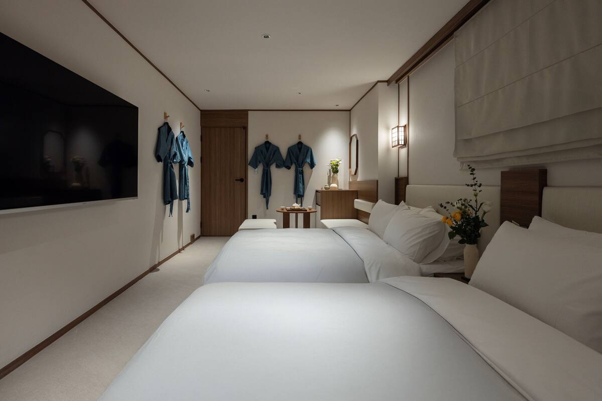 Een hotelkamer met een groot bed, een kleiner bed, een televisie en een spiegel.