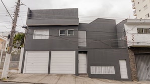 En modern tvåvåningsbyggnad med ett garage, ett litet fönster och en dörr.