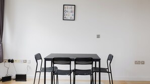 Quarto com uma mesa, quatro cadeiras, uma tomada e um quadro na parede.