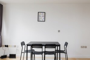 Ein Zimmer mit einem Tisch, vier Stühlen, einer Steckdose und einem gerahmten Bild an der Wand.