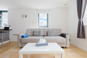Ein modernes Wohnzimmer mit einer Couch, einem Couchtisch und einem Fenster.