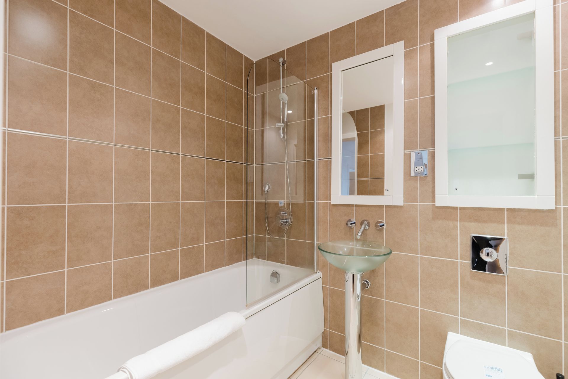 Une salle de bain avec une baignoire, un lavabo en verre et des toilettes.