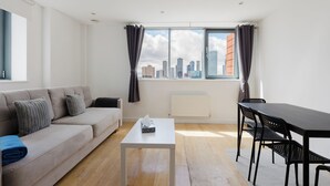 Uma sala de estar moderna com um sofá, uma mesa de centro, uma mesa de jantar com cadeiras e uma grande janela com cortinas.
