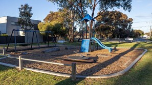 A playground with swings, a slide, and a climbing structure.