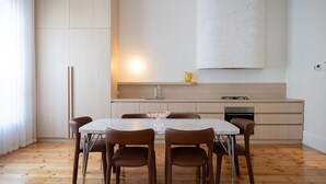 Una cocina moderna con una mesa de mármol, sillas marrones y acabados en madera clara.