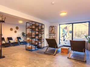 Ein Zimmer mit großem Fenster, einer an der Wand befestigten Ablage mit Handtüchern, zwei Korbstühlen und einer Stehlampe.