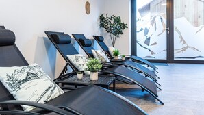 A modern spa room with reclining chairs, a small table with plants, and a large window with a view of a building. - Ski-in, ski-out in Alpine style and sauna (Hinterglemm)