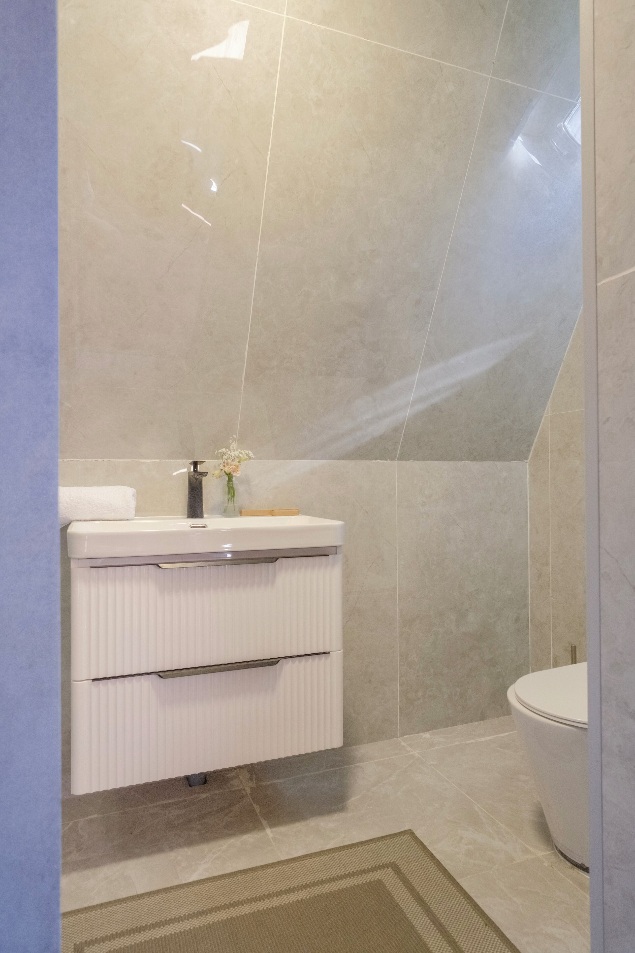 A modern bathroom with a white vanity, a toilet, and a shower area.