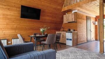 L’intérieur d’un chalet en bois comprend un coin repas, une cuisine et un canapé.