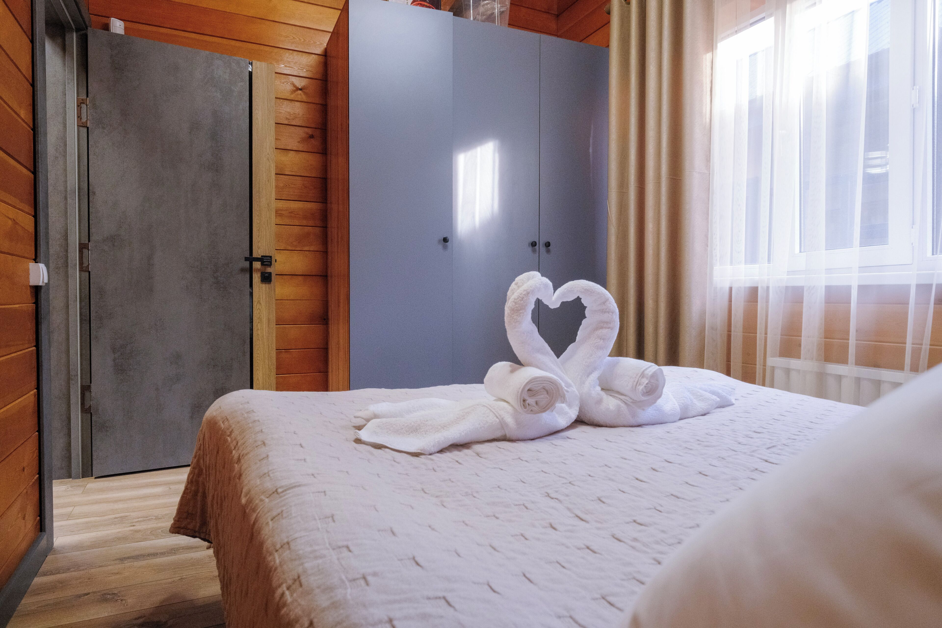 A hotel room with a bed, a wardrobe, and a window.