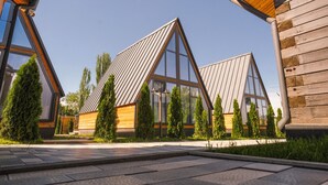 A modern building with a triangular roof and large windows, surrounded by greenery.