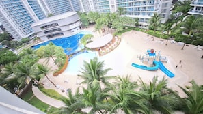 A resort with a swimming pool, palm trees, and a water slide.