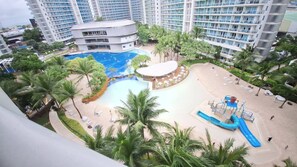 A resort with a central pool, palm trees, and a water slide.