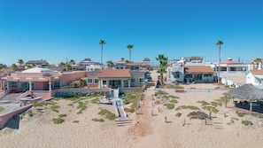 Ein Küstenresort mit mehreren Gebäuden, einem Sandstrand und Palmen.