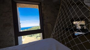 Une pièce avec un lit, une fenêtre donnant sur un paysage et un espace protégé par un moustiquaire.