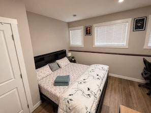 A bedroom with a bed, bedside tables, a desk, and a chair.