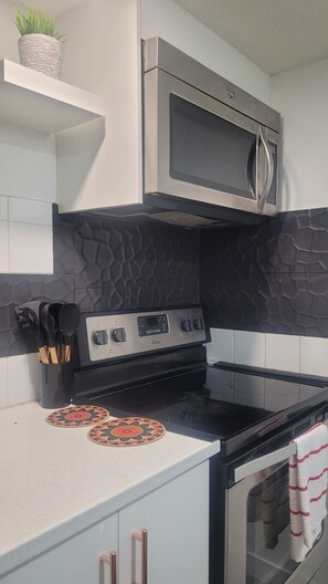 Uma cozinha com micro-ondas de aço inoxidável, fogão a gás e forno preto.