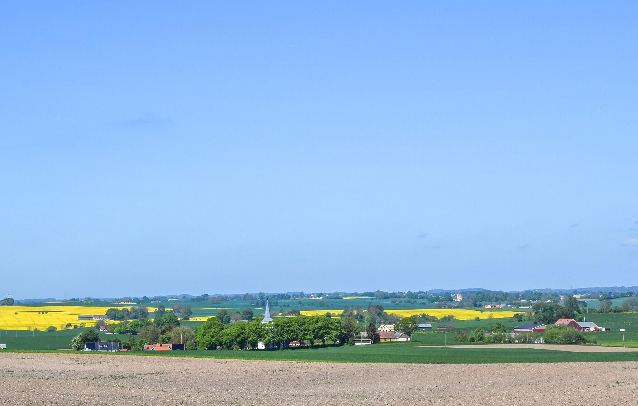 A rural landscape with fields, a church, and scattered houses.