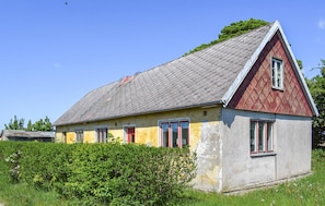 A small, single-story house with a sloped roof, a red and yellow facade, and a window with a red frame. - Awesome home in Ystad with WiFi (Ystad)