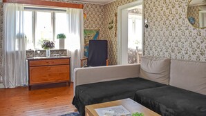 Ett rum med en byrå i trä, en soffa, ett litet bord, en spegel och ett fönster med gardiner.