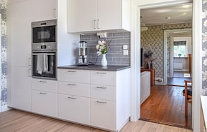 A modern kitchen with built-in appliances, a coffee machine, and a vase with flowers. - Awesome home in Ystad with WiFi (Ystad)