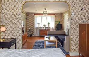 Ein Zimmer mit einem Bett, einem Schlafsofa, einem kleinen Tisch, einem Schrank, einem Spiegel, einem Fenster und einer Chandeliebre.