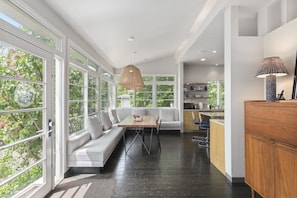 A modern kitchen with a dining area, large windows, and a hanging light fixture. - Sunlit Updated Victorian - Chef`s kitchen, library and sunroom, Boston 20 min by car or train (Melrose)