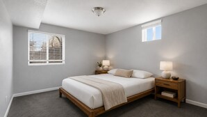 A bedroom with a bed, bedside tables, a nightstand, a ceiling light, and a window with blinds. - 1,100 sf Spacious Cozy 2BR Near Denver DT, Red Rocks, and Rockies! (Arvada)