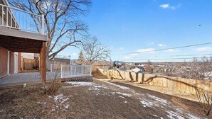 A residential backyard with a wooden deck, a fenced area, and a clear sky. - 1,100 sf Spacious Cozy 2BR Near Denver DT, Red Rocks, and Rockies! (Arvada)