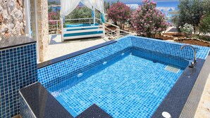 A stone building with a pool and a bed with a canopy.