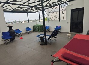 A covered outdoor area with blue chairs, a red table, and a small dog. - APARTMENT FOR SALE IN MEXICO CITY, near downtown (Ciudad de México)