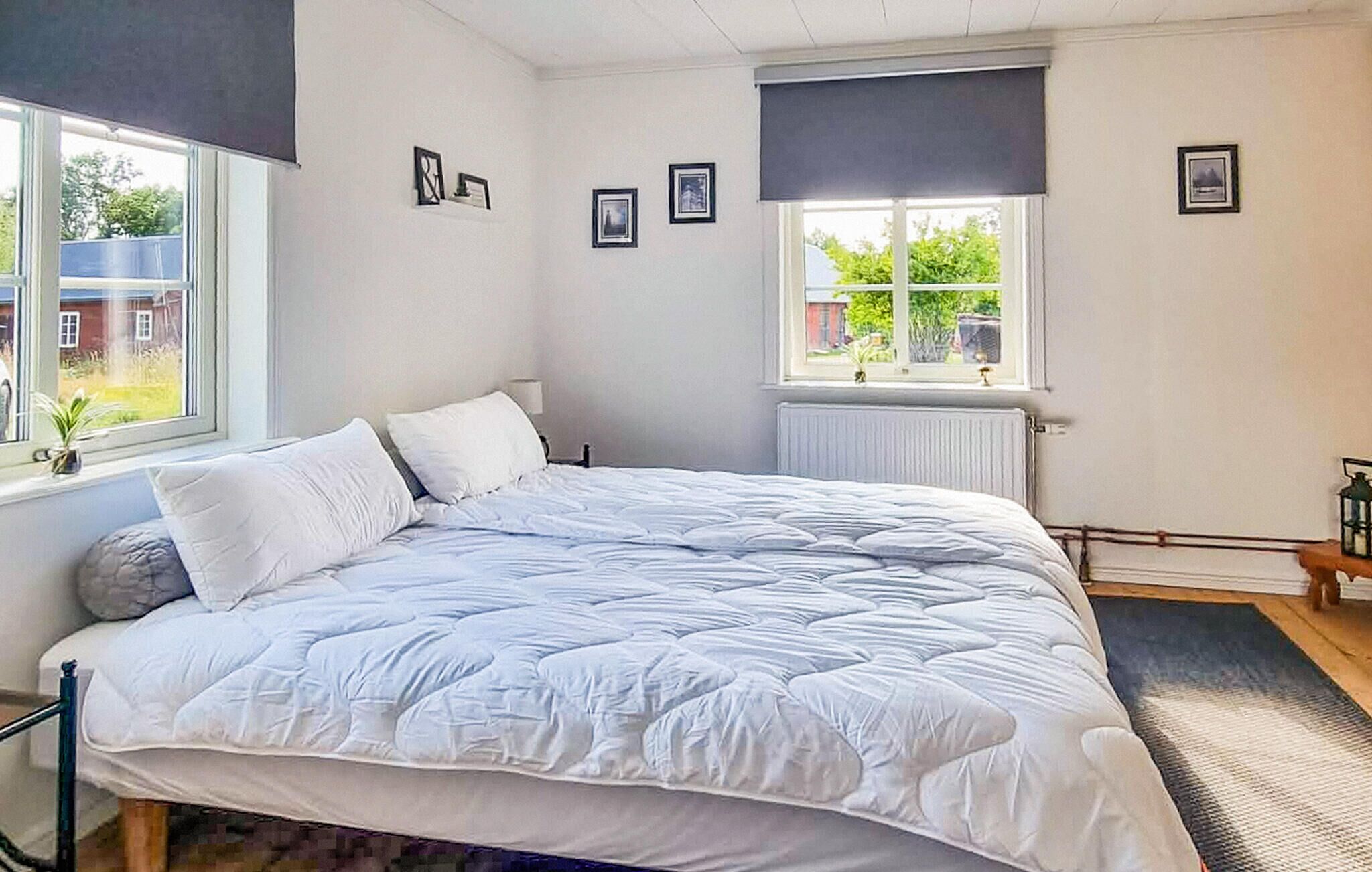 Une chambre avec un grand lit, une fenêtre donnant sur la verdure et un radiateur.