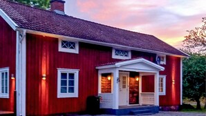 A red two-story house with a white porch and a chimney. - 2 bedroom lovely home in Lönashult (Lönashult)