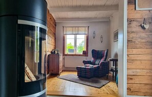 A cozy room with a fireplace, a plaid armchair, and a window with curtains. - 2 bedroom cozy home in Lönashult (Lönashult)