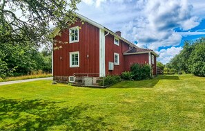 Une maison rouge à deux étages, avec une pelouse bien entretenue et un ciel dégagé.