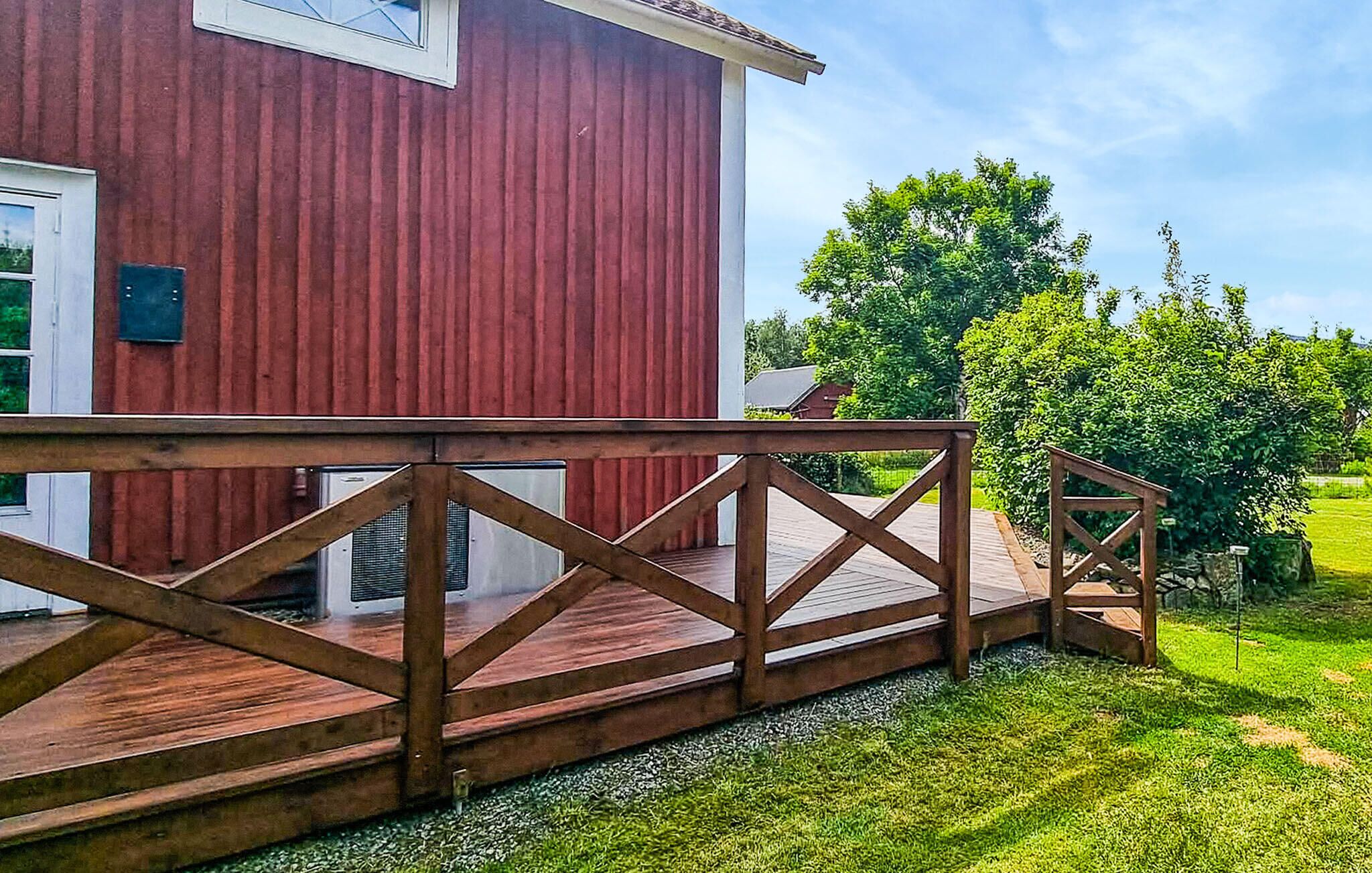Un bâtiment rouge avec une terrasse en bois menant à une porte blanche.