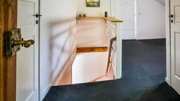 Ein Flur mit einer Tür zu einem Zimmer, das ein Bett und einen kleinen Tisch hat.