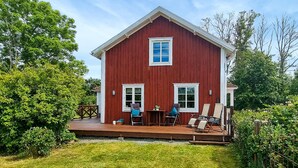 A red wooden house with a porch, two windows, and a small table with chairs. - 2 bedroom lovely home in Lönashult (Lönashult)