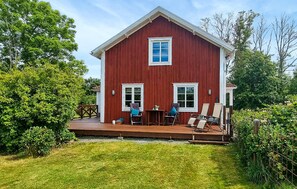 A red wooden house with a porch, two windows, and a small table with chairs. - 2 bedroom lovely home in Lönashult (Lönashult)