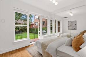 Ein Schlafzimmer mit großem Fenster, einem Bett und Blick auf einen Garten.